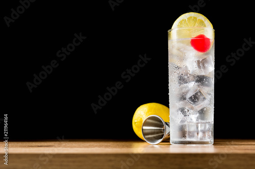 Classic Tom Collins cocktail on wooden table and black background. Copyspace