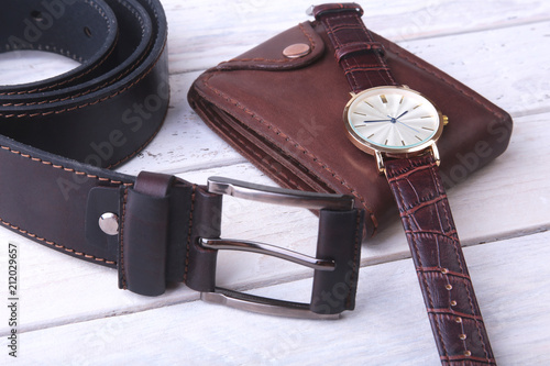 Men's accessories for business and rekreation. Leather belt, wallet, watch and smoking pipe on wood background.. Top view composition.