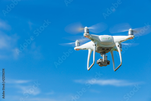 Flying drone quadcopter with digital camera on blue sky