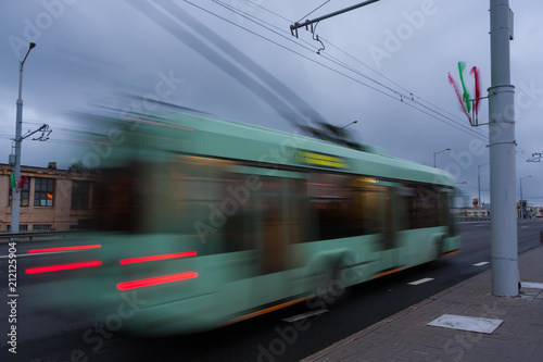 Movement of a blurred trolleybus at dusk along the street. 