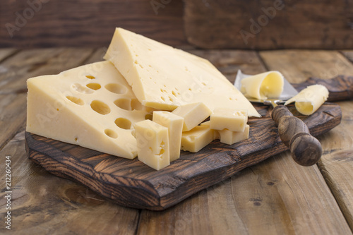 Cheese with holes large and small. Wooden board and knife. Traditional Dutch cheese. Copy space