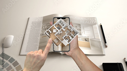 Augmented reality concept. Hand holding smartphone with AR application used to simulate 3d pop-up interactive house maps to life