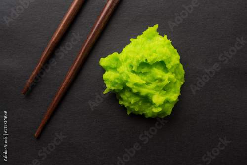 Green wasabi sauce or paste in bowl, with chopsticks or spoon over plain colourful background. selective focus