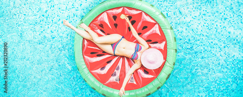 Top view of young woman relaxing on watermelon lilo in villa resort pool