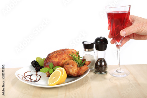 Pieczony kurczak i lampka czerwonego wina w dłoni.