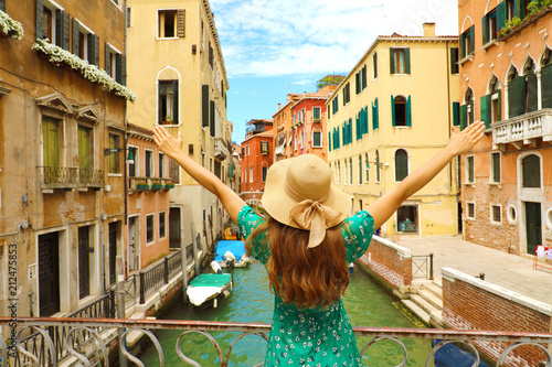 Europe travel vacation fun summer woman with arms up and hat happy in Venice, Italy. Carefree girl tourist in European destination wearing green fashion dress. 