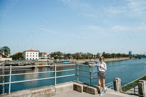 Stylish girl near the Vistula River in Krakow. Bridge across the river in Krakow. Young woman in town. Lady with a mobile phone. Travel to Poland.