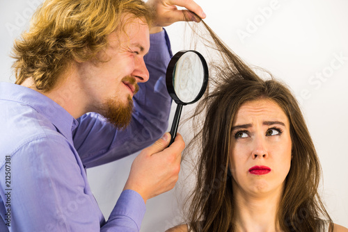 Man looking at woman hair using magnifer