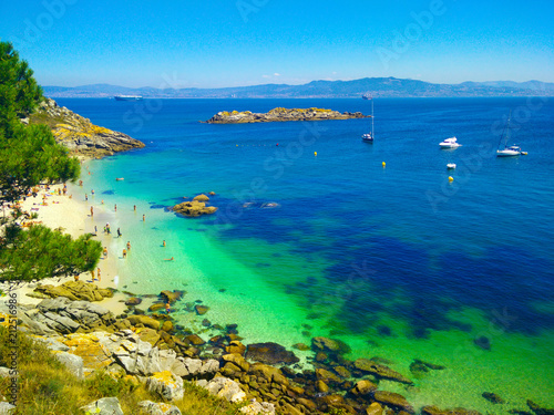 Beach with transparent green water in Cies Islands, in Galicia, Spain, with boats docked in front of