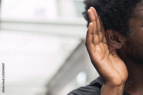 african man hearing or listening; portrait man listening to hearsay, rumor, gossip, good or bad news; communication, information, rumor concept; african man or black man young adult model