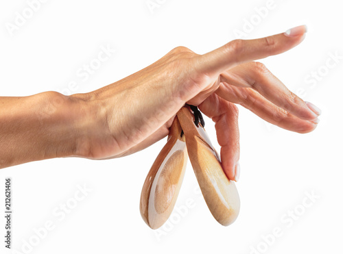 castanets in the hand of a young girl with thin graceful fingers on a white background