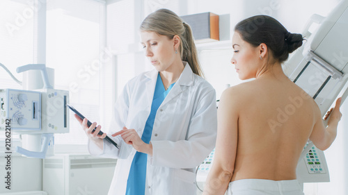 In the Hospital, Mammography Technologist / Doctor adjusts Mammogram Machine for a Female Patient. Friendly Doctor Explains Importance of Breast Cancer Prevention Screening. Modern Clinic.