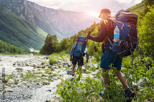 Tourists with hiking backpacks on beautiful mountain landscape background. Climbers hike to mounts. Group of hikers walking in mountains