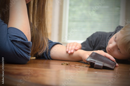 A sad woman at the table thinks the last coins. Empty wallet - boy son calms mother.