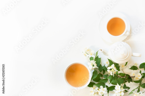 Green jasmin tea and jasmine flowers, cup of green tea on white. Top view. Teatime. Copy space.