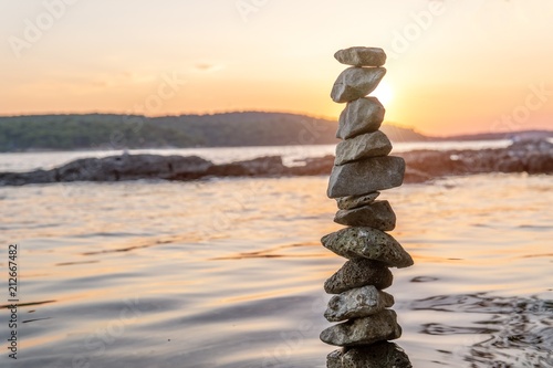 Zen balanced stones stacked on sea coast at sunset. Balance and equilibrium concept.