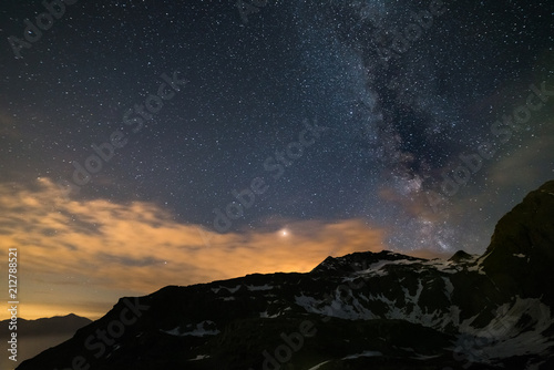 Astro night sky, Milky way galaxy stars over the Alps, stormy sky, Mars planet beyond the clouds, snowcapped mountain range