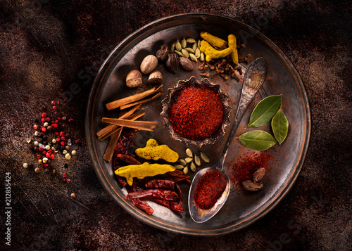 Indian spices and herbs on a plate on a dark concrete background