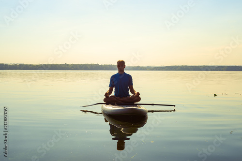 Man practicing yoga on a SUP board