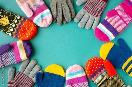 Mittens and gloves of different colors. View from above. Clothes for cold autumn and winter in the form of mittens and gloves. Warm clothing on a turquoise background.