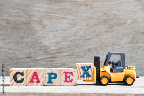 Toy forklift hold letter block x to complete word capex (abbreviation of capital expenditures) on wood background
