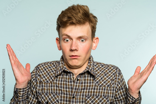 uncomprehending bewildered puzzled perplexed confused man. portrait of a young guy on light background. emotion facial expression. feelings and people reaction.