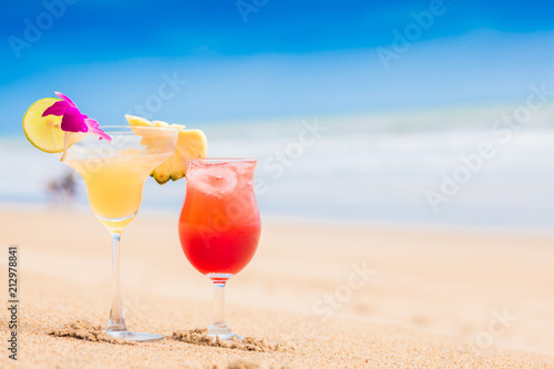 two perfect cocktails strawberry daiquiri and Margarita with lime and pineapple on top, beach background