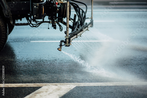 Cleaning sweeper machines washes the city asphalt road with water spray.