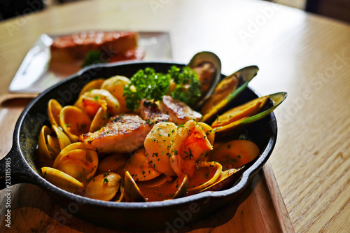 Sizzling hot Bouillabaisse,a traditional Provençal fish stew, with lots of seafood such as fish, shrimp, clams, mussels and enhance with saffron in a black cast iron pan served with Rouille.