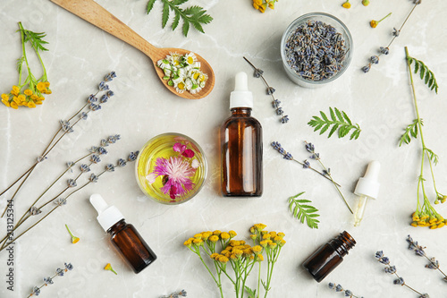 Flat lay composition with essential oils and flowers on light background