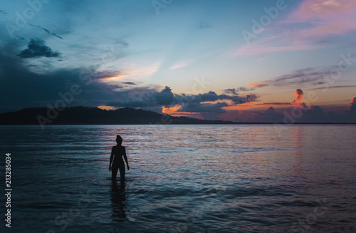 Sunset silhouette of Millennial female traveller standing in the Caribbean Sea off the coast of Puerto Viejo, Costa Rica