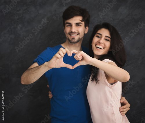 Smiling couple making heart shape by fingers