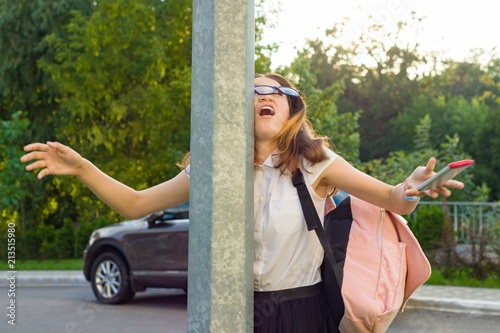 Portrait of young inattentive girl, distracted by mobile phone. Girl crashed into street post, dropped phone.