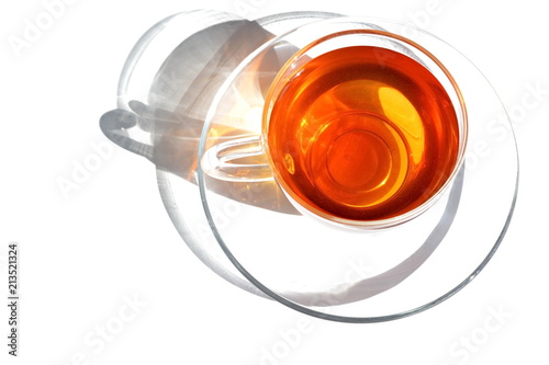 glass transparent cup of warm tea and dish in morning bright rays sunlight with shadow on white background. Isolated. Top view