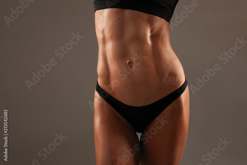 Sporty sexy girl with great abdominal muscles in black sportswear on black background. The pack abs on your stomach