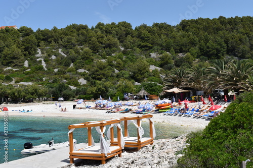 Beach cabanas and motorboat on the Dalmatian coast of the turquoise Adriatic sea in Europe. Fantastic sheltered shingle bay and public beach summer in Croatia Sunbeds and parasols against extra charge