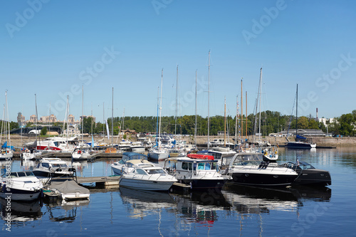 Modern yacht club with various motor and sail boats moored to pier floating on water in summer