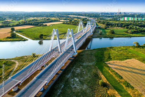 New modern double cable-stayed bridge over Vistula River in Krakow, Poland. Part of the ring motorway around Krakow under construction. Aerial view at sunset. Sedzimir Steelworks in the background.