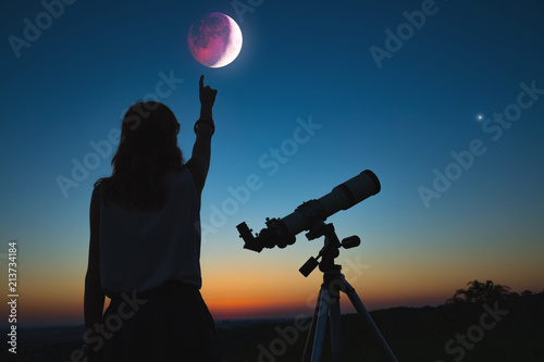 Girl looking at lunar eclipse through a telescope. My astronomy work.