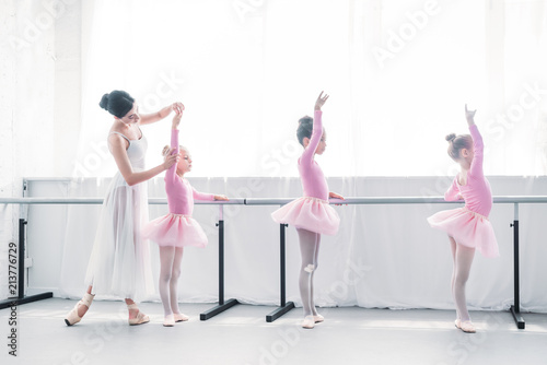 side view of ballet teacher exercising with children in ballet school