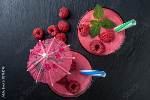 Raspberry smoothie or milk shake in a glass on dark background, top view