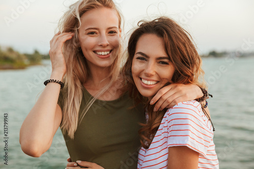 Women friends hugging outdoors on the beach.