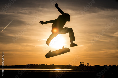 Skater make trick kickflip against the beautiful orange sunset