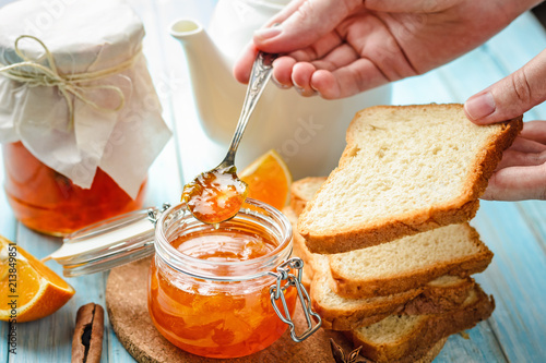 woman spreads toasts with orange jam from glass jar