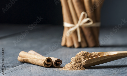 Close up cinnamon sticks and powder healthy spice on black wooden background 
