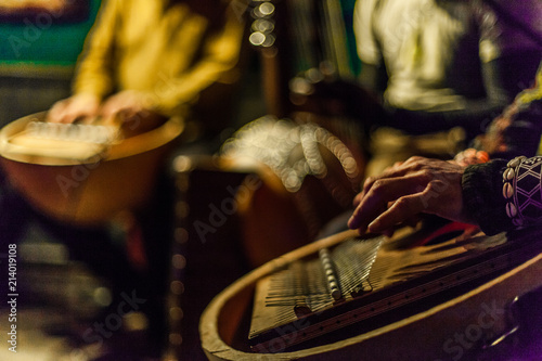 Man's hands playing kalimba with blurry musicians playing african instruments live on stage