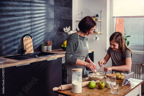 Mother and daughter making dough for apple pie