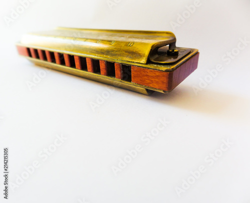 Old golden diatonic harmonica with ten holes, focused close up on white background and with blur effect.