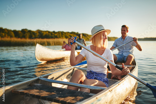 Laughing young woman canoeing on a lake with friends