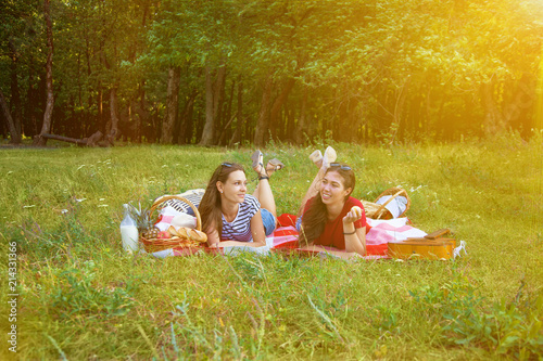 Two beautiful girls rest on a picnic in the forest